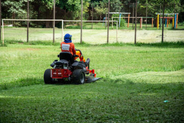 Lawn mower cutting grass in a large green field 