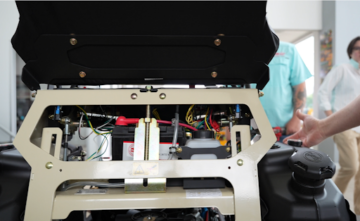 Technician performing routine engine maintenance on a zero-turn mower inside a service shop