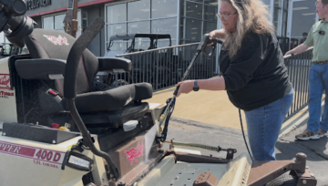 Technician cleaning the front of a mower using a pressure washer